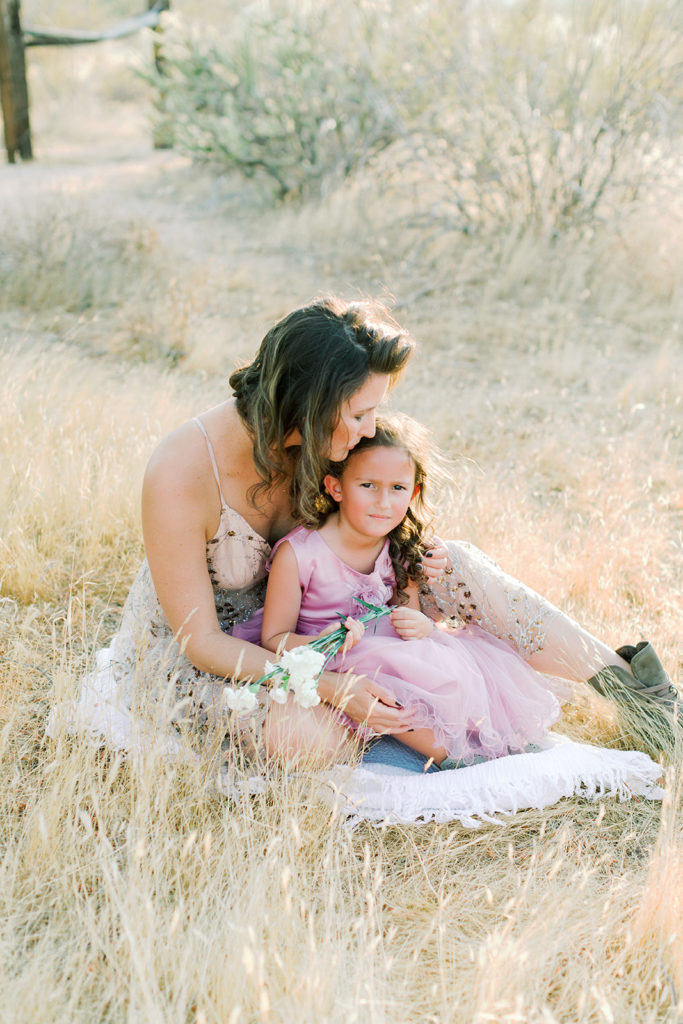 Mom and daughter sit in the tall Arizona grass