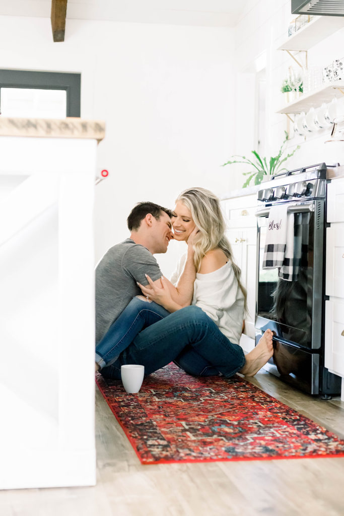 Examples of lifestyle photography - young couple laughs and kisses on the kitchen floor